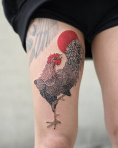 White rooster and red sun Korean minhwa tattoo on the thigh