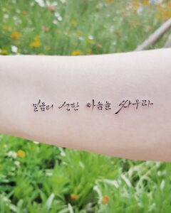 Korean lettering tattoo 믿음의 선한 싸움을 싸우라 in thin brush script on the forearm, Seoul